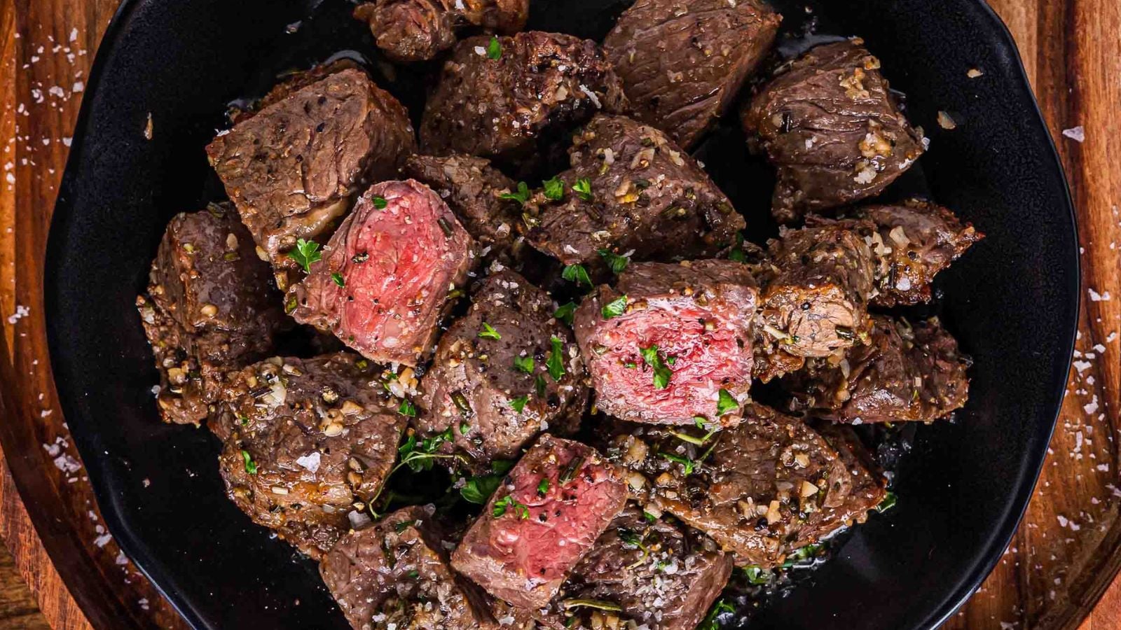 Air fryer steak bites coated in garlic butter served hot with crispy browned edges.