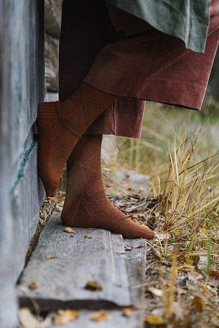 A close up of a pair of feet in burnt orange socks. The socks have a textured triangle pattern 