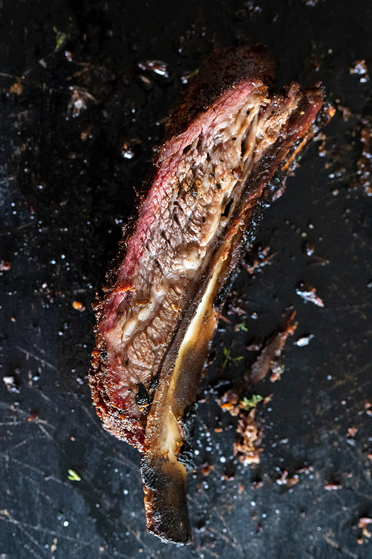 one smoked dino rib on a black board.