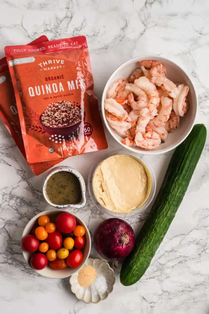 Ingredients to make a greek shrimp bowl on a marble countertop.