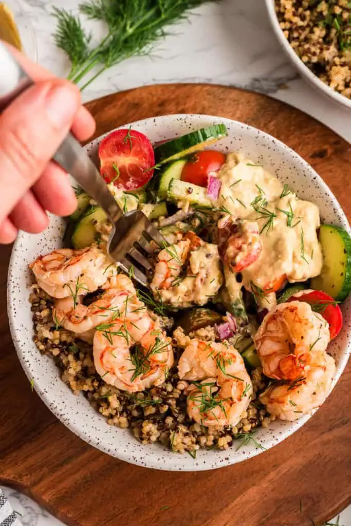 Fork digging into a greek shrimp quinoa bowl