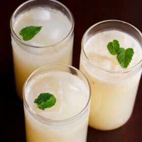 Lychee juice garnished with mint sprigs in three glasses.