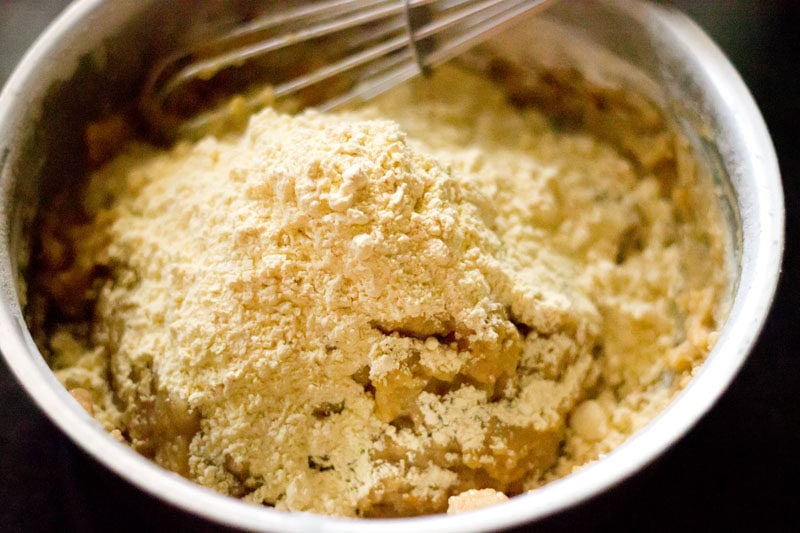 Mound of gram flour on top of orange biscuit ingredients.