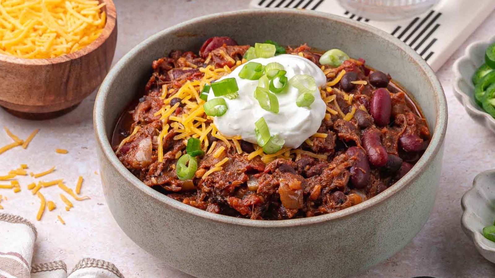 Hearty bowl of pulled pork chili with smoky chunks of pork and beans throughout.
