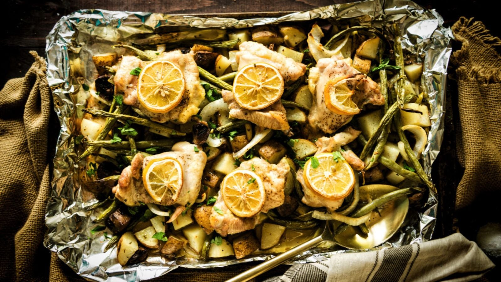 Chicken thighs roasted on sheet pan with lemons and potatoes caramelizing.
