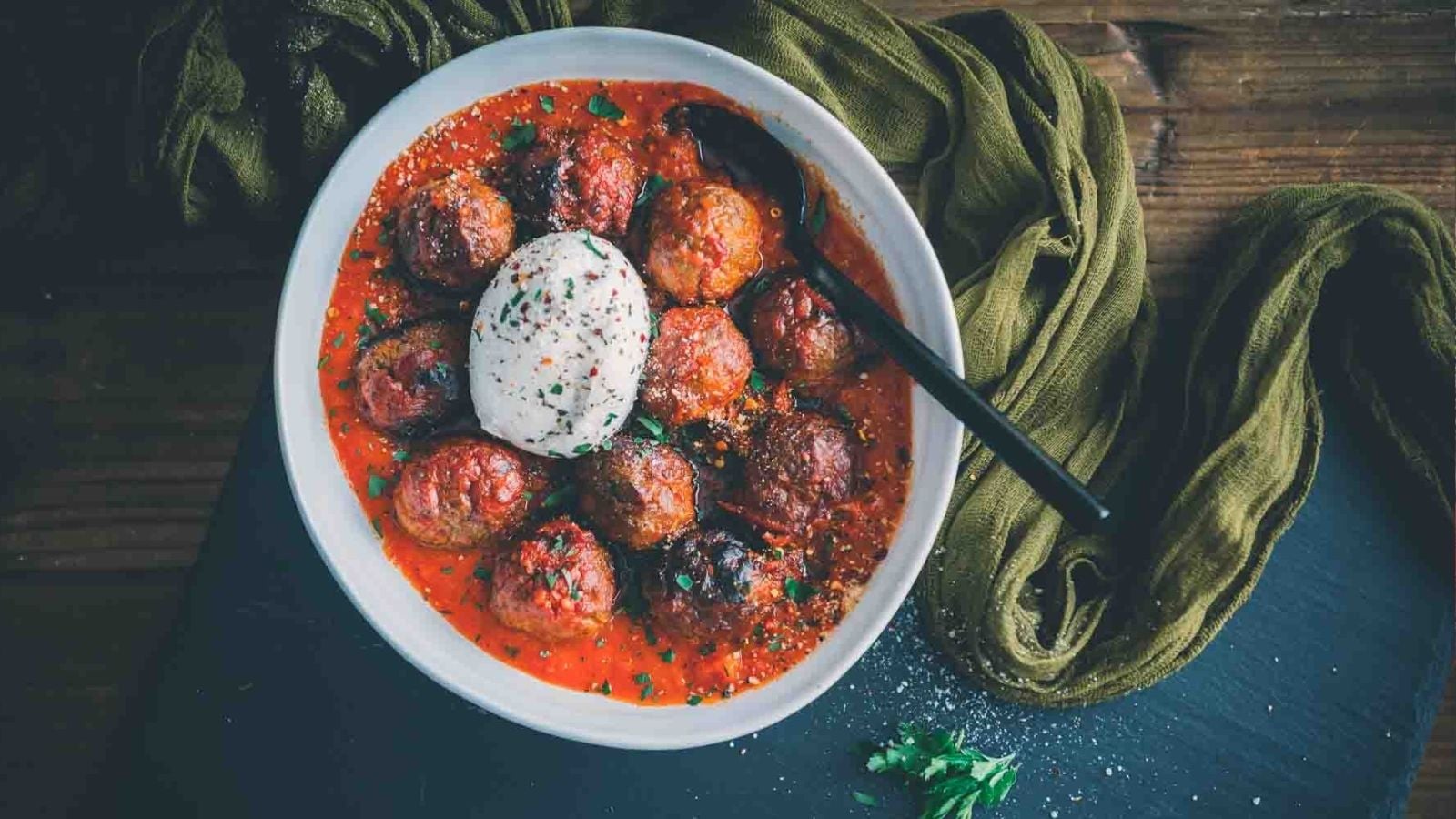 Smoked meatballs with browned crust arranged on a tray with herbs scattered.