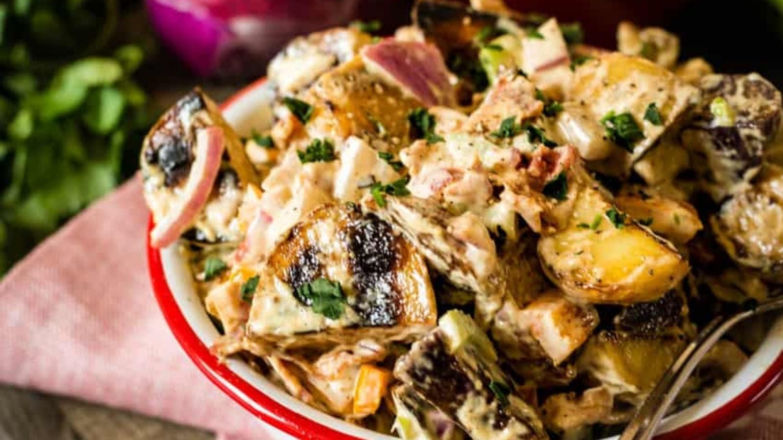 Potato salad mixed with smoked potatoes and creamy dressing throughout.