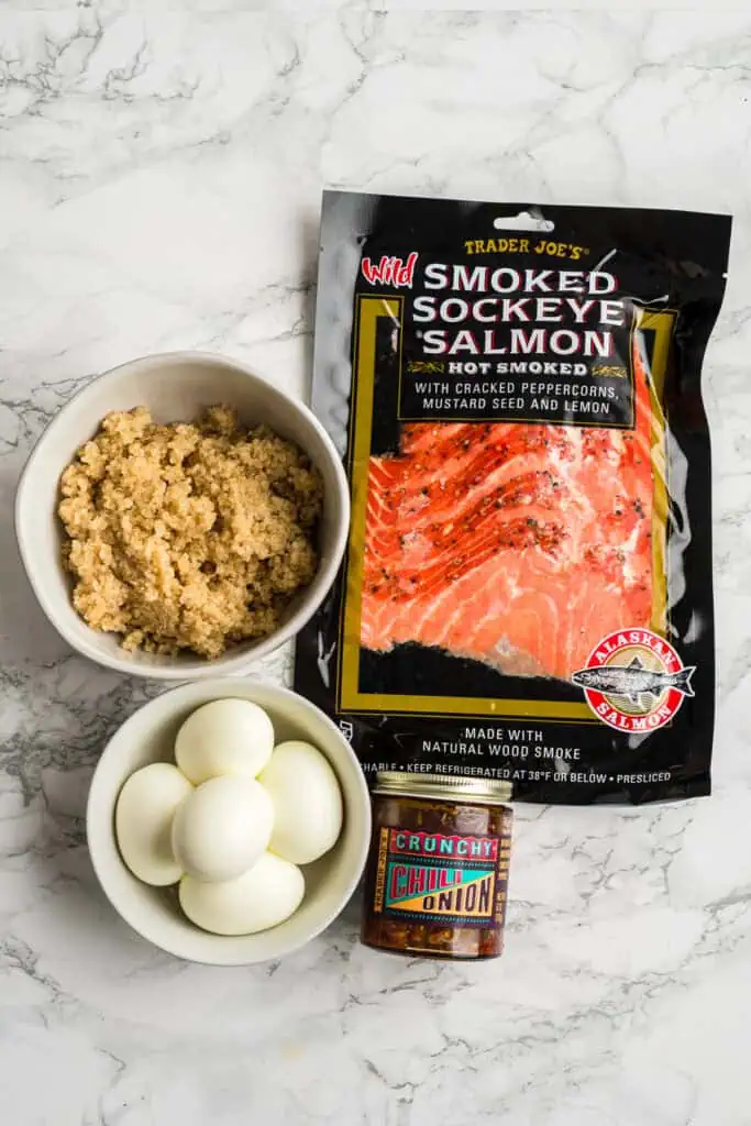 Ingredients to make smoked salmon quinoa bowls on marble countertop.