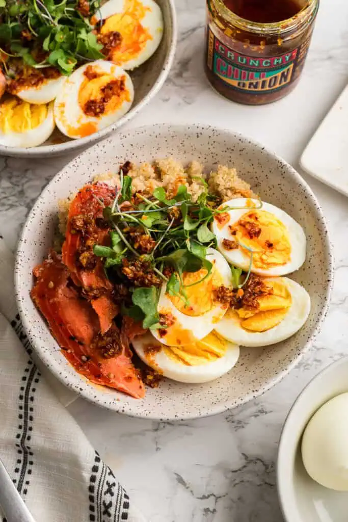 Smoked salmon quinoa and hard boiled eggs in a white bowl.