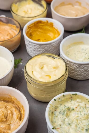 A variety of aiolis in bowls on a table.
