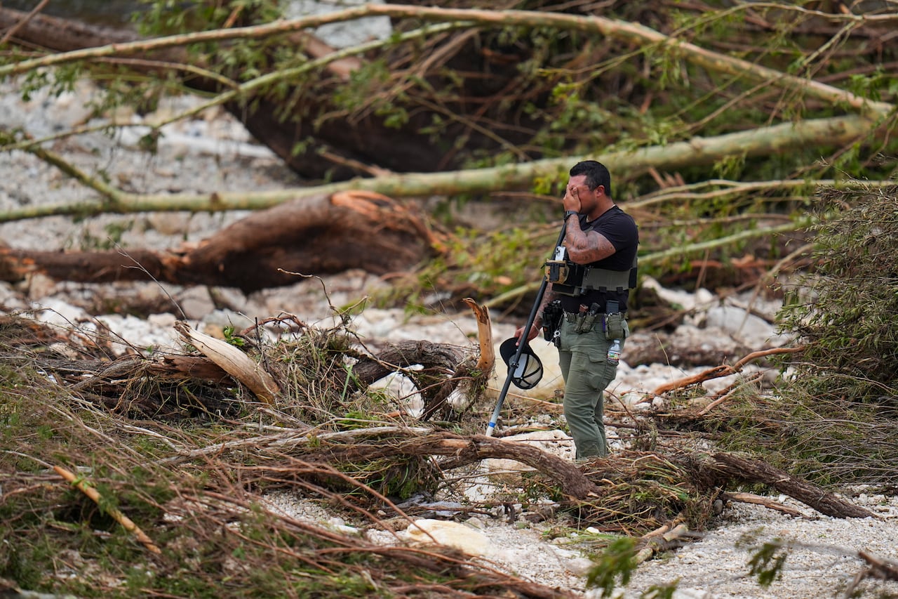 A man crying, standing in deep water and broken trees
