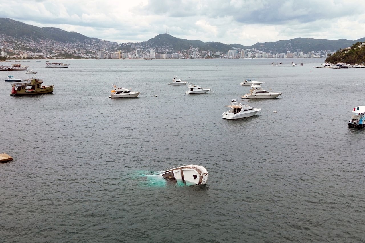 A small boat is flipped over, amid a collection of a number of boats docked in a body of water.