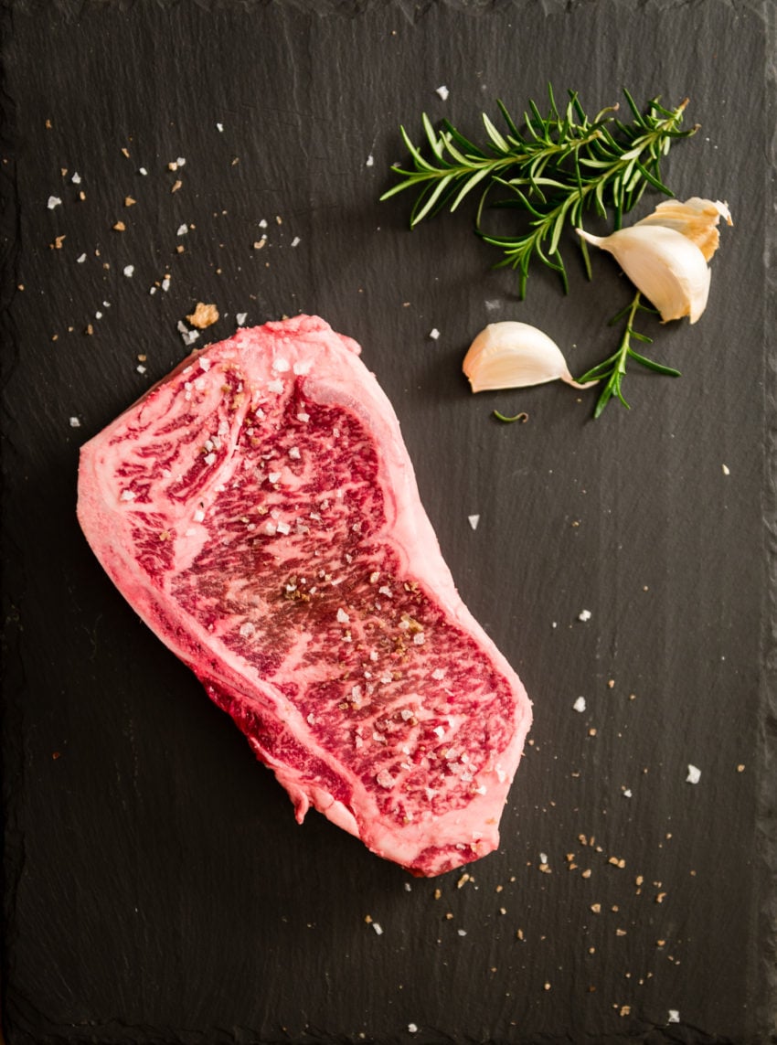 New york strip steak with flakey salt on a slate board.