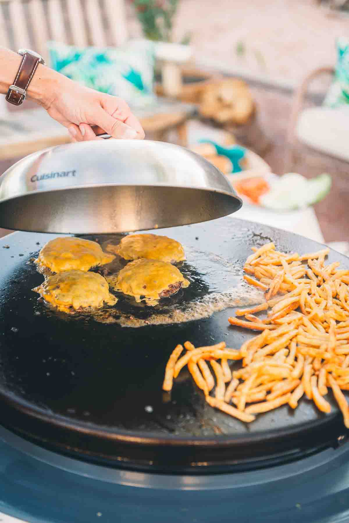 Cheese being melted with a dome on the griddle.