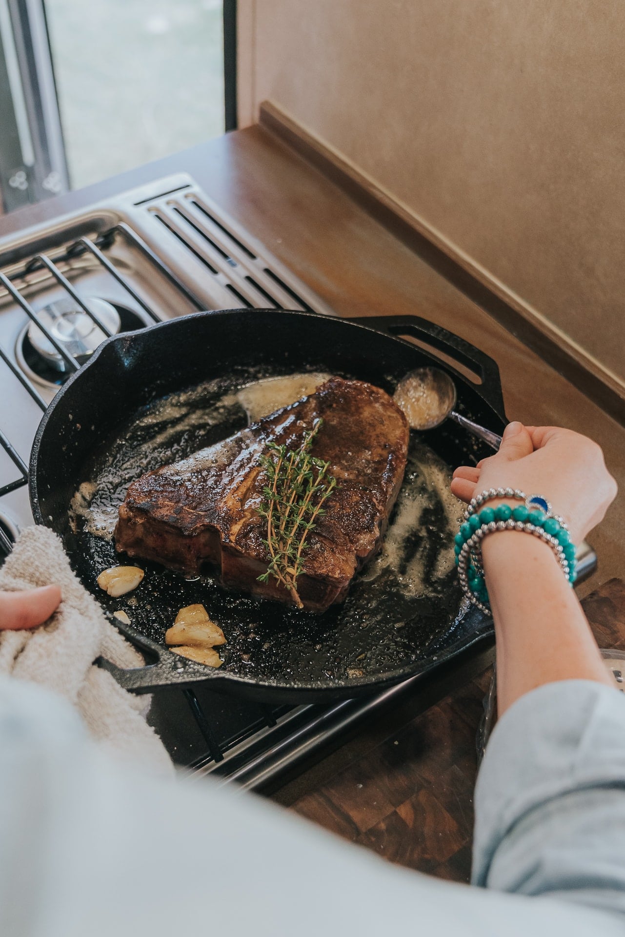 Porterhouse steak in a skillet with garlic and herbs.