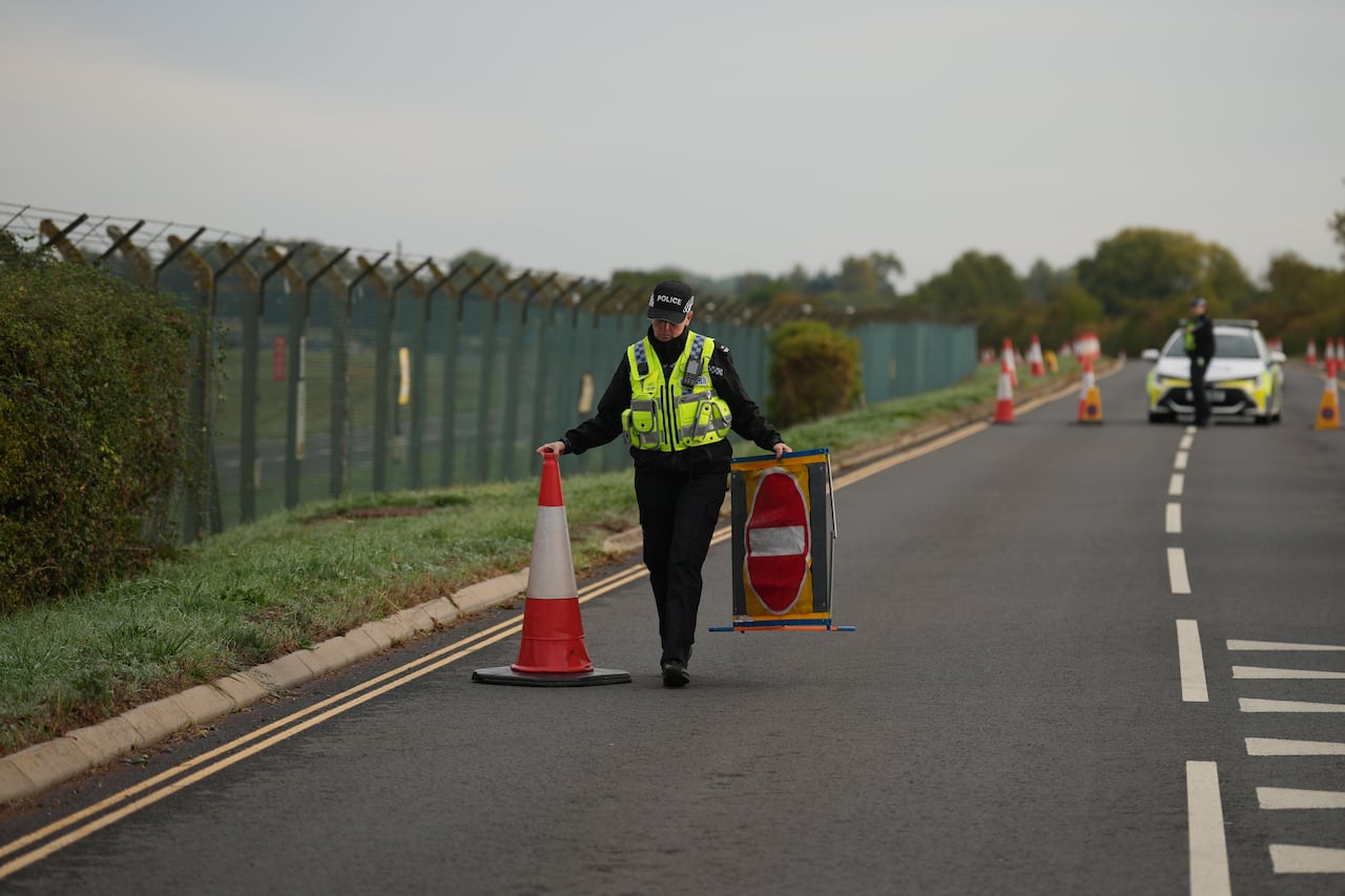 A police officer puts a pylon down on a road.