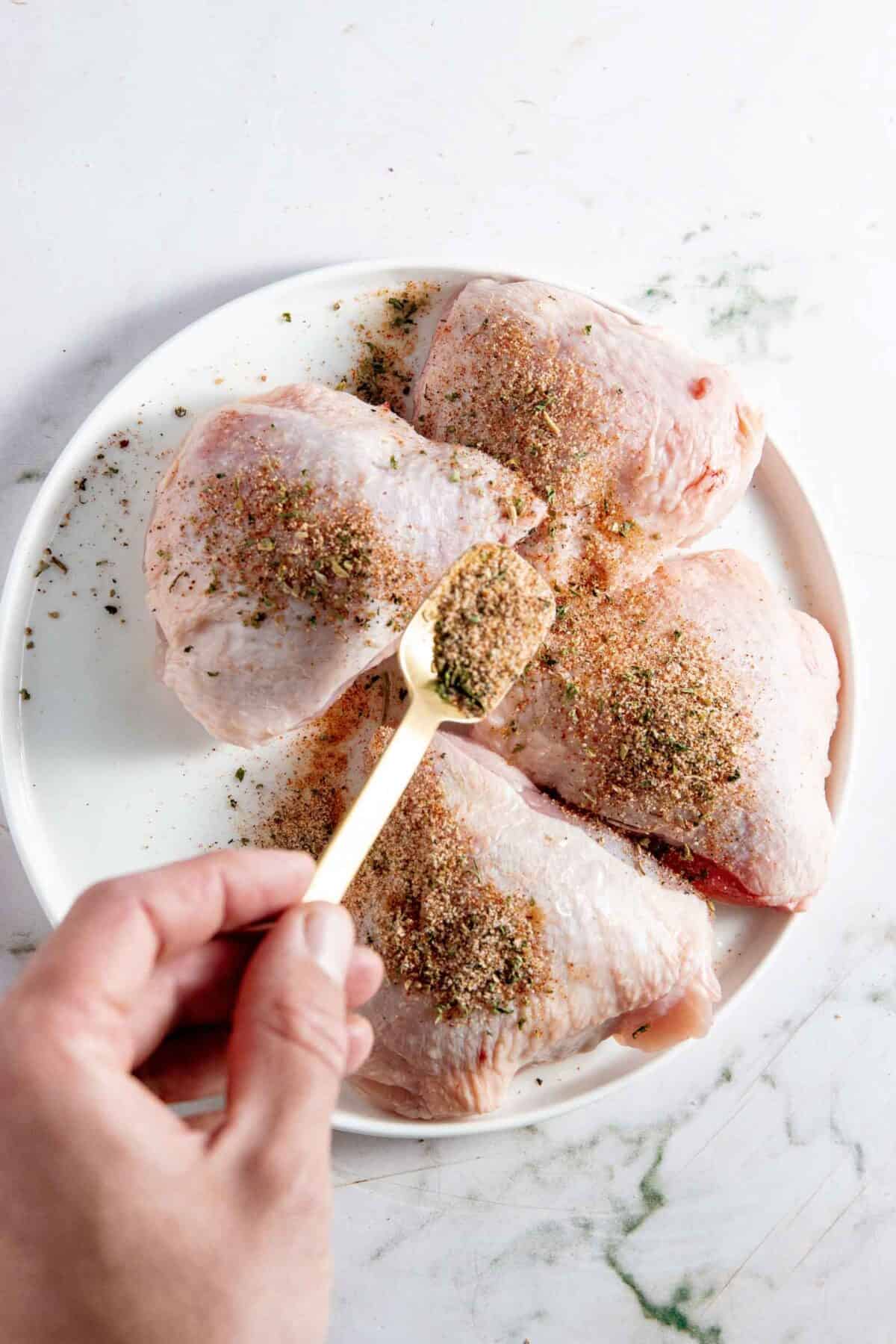 Sprinkling spices on thighs.