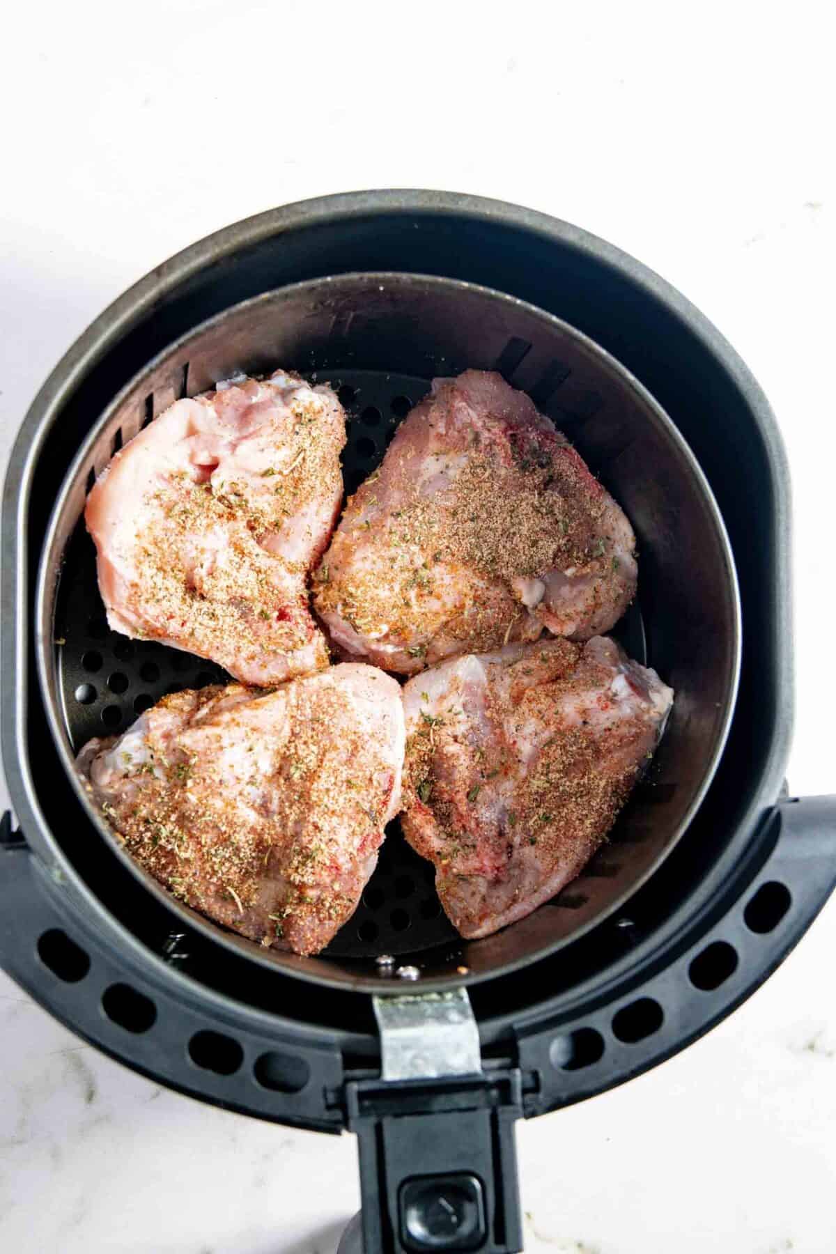 Raw chicken placed in the air fryer basket.