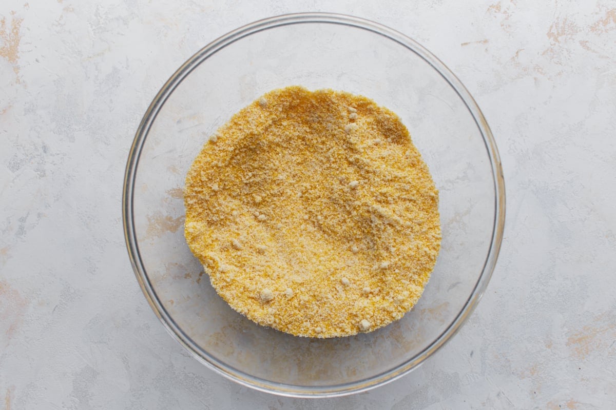Almond flour, cornmeal, baking powder, baking soda, and salt whisked together in a glass mixing bowl.