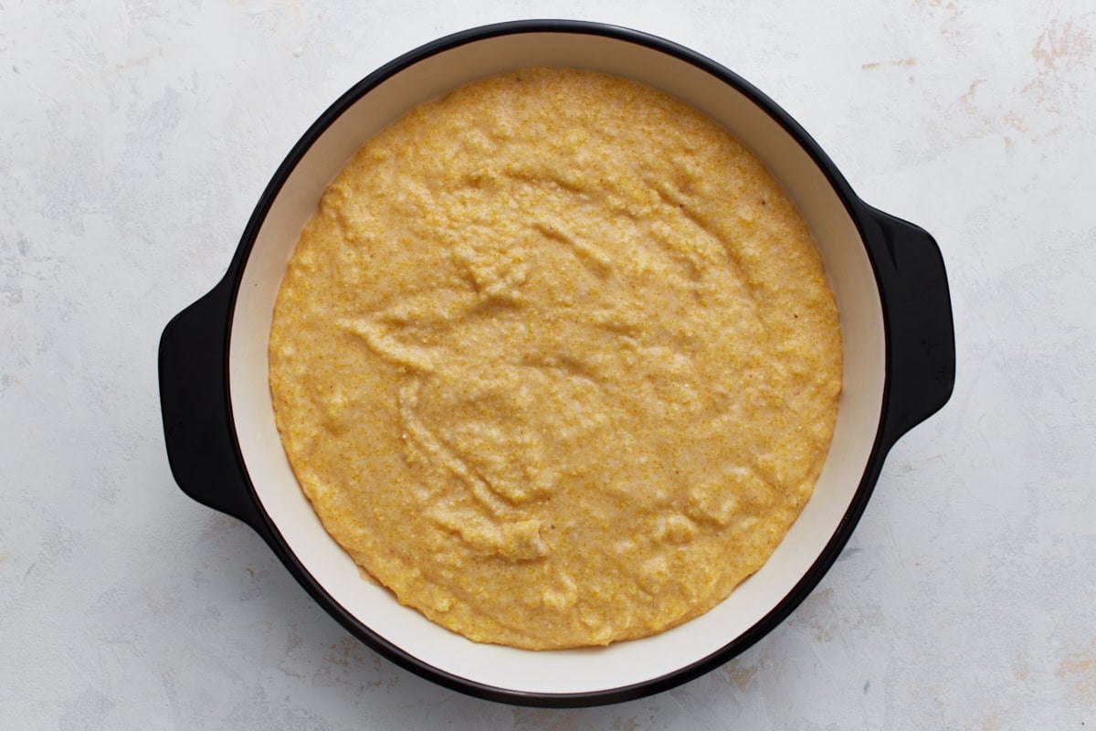 Almond flour cornbread batter spread evenly in a round baking dish before baking.