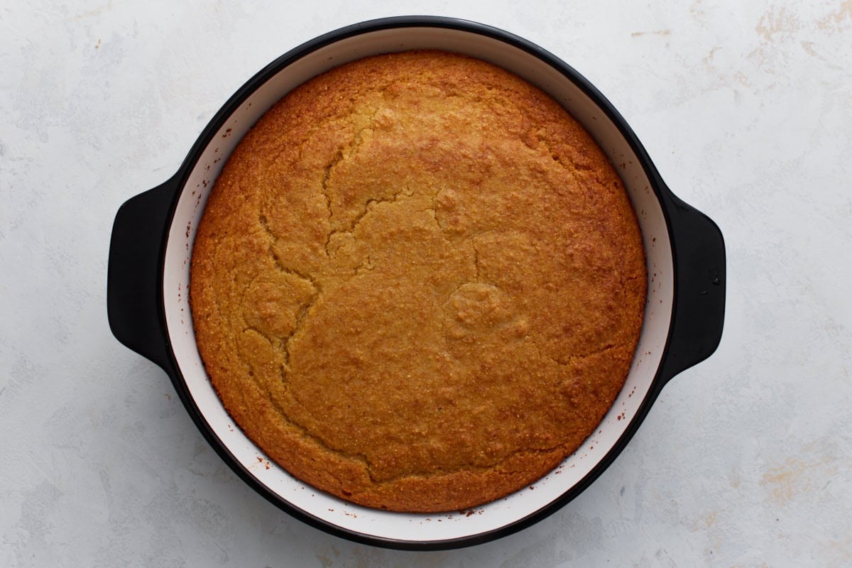 Golden brown almond flour cornbread fresh out of the oven in a round baking dish.