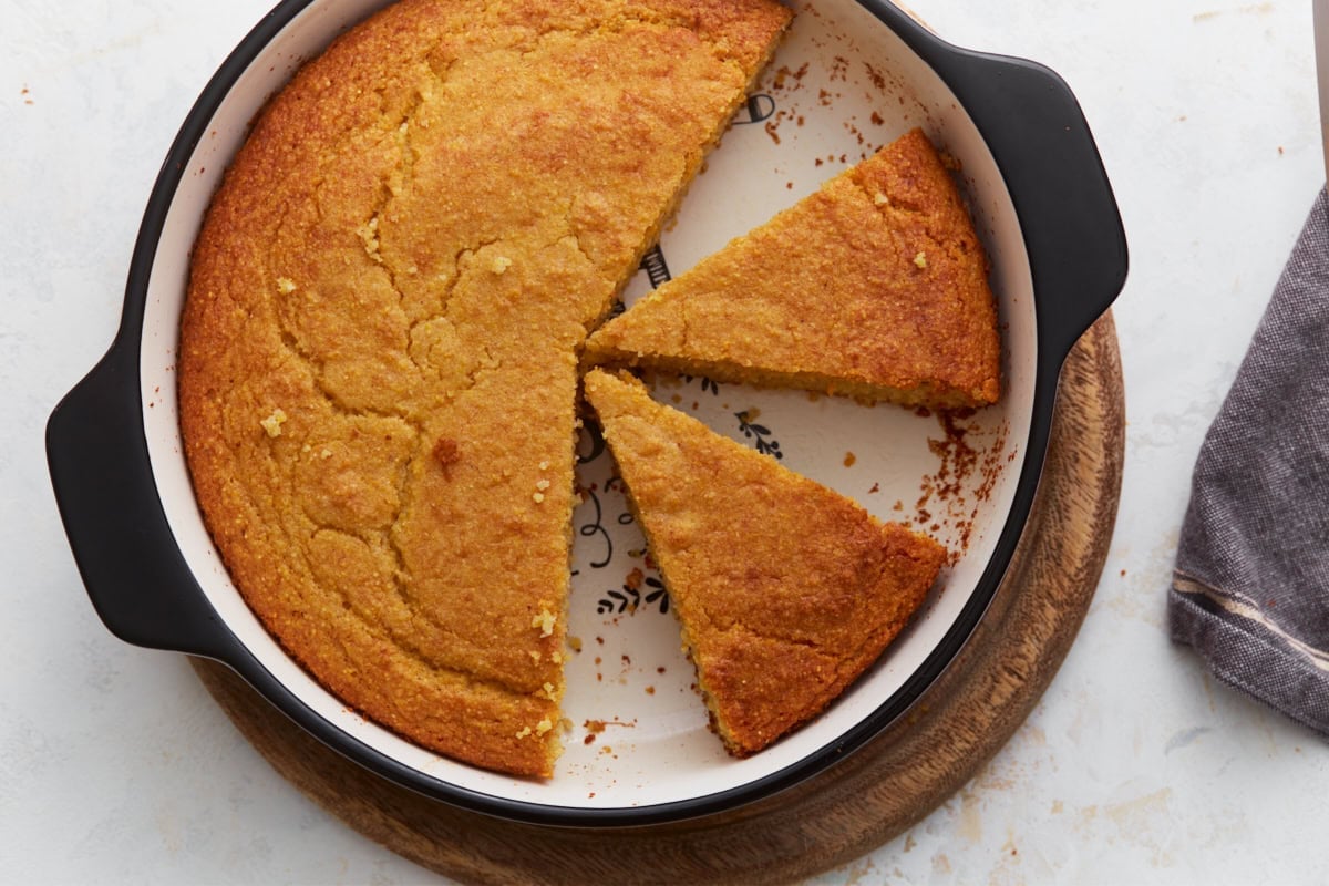 Almond flour cornbread in a round baking dish with two wedges sliced and pulled out.