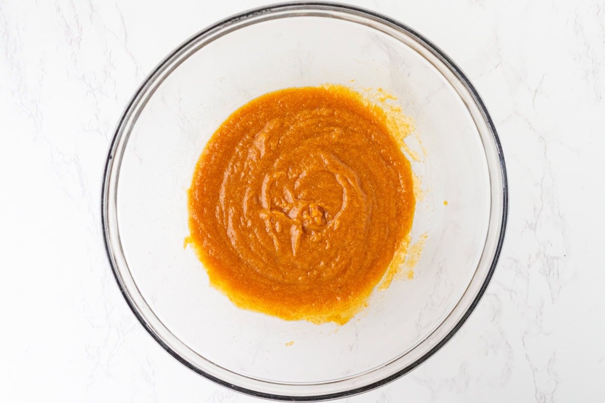 Pumpkin puree, melted butter, brown sugar, maple syrup, egg, and vanilla whisked together in a glass mixing bowl.