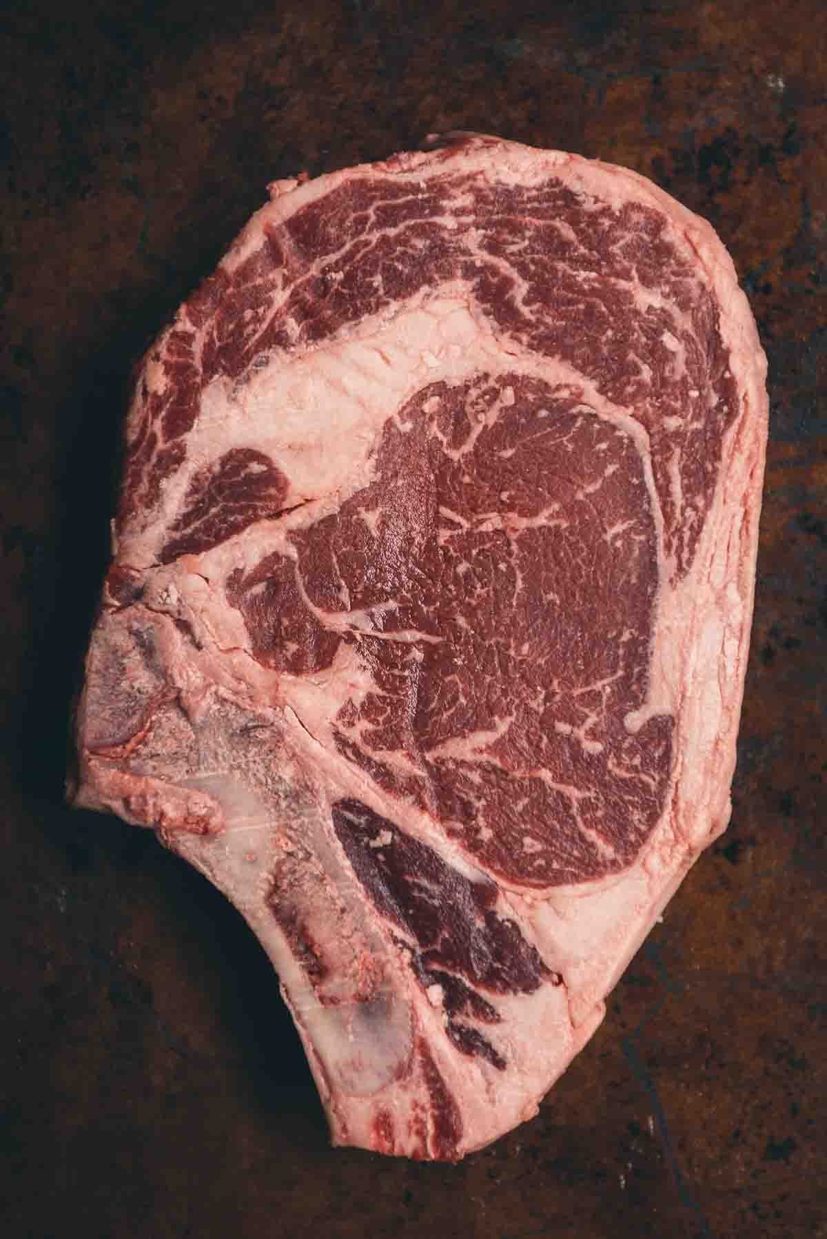 Close up of dry-aged ribeye steak to show marbling and fat.