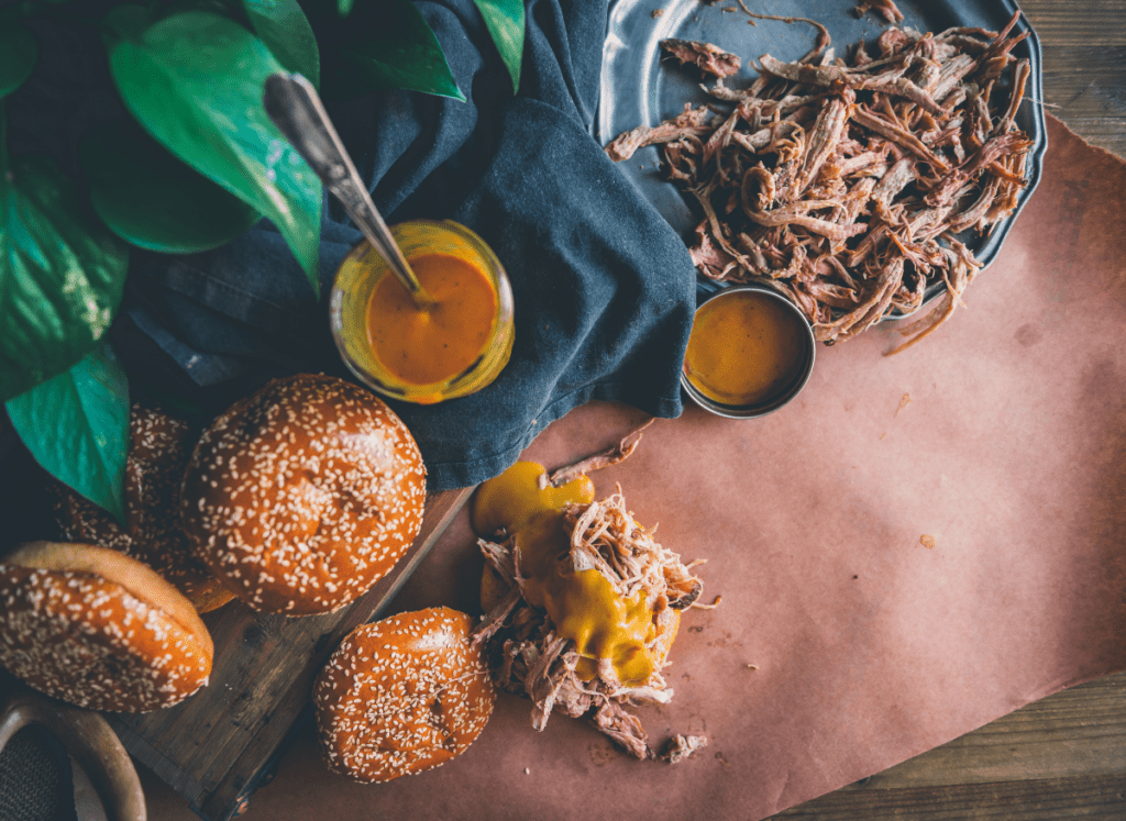 Overhead shot of Carolina bbq sauce with buns and pulled pork.