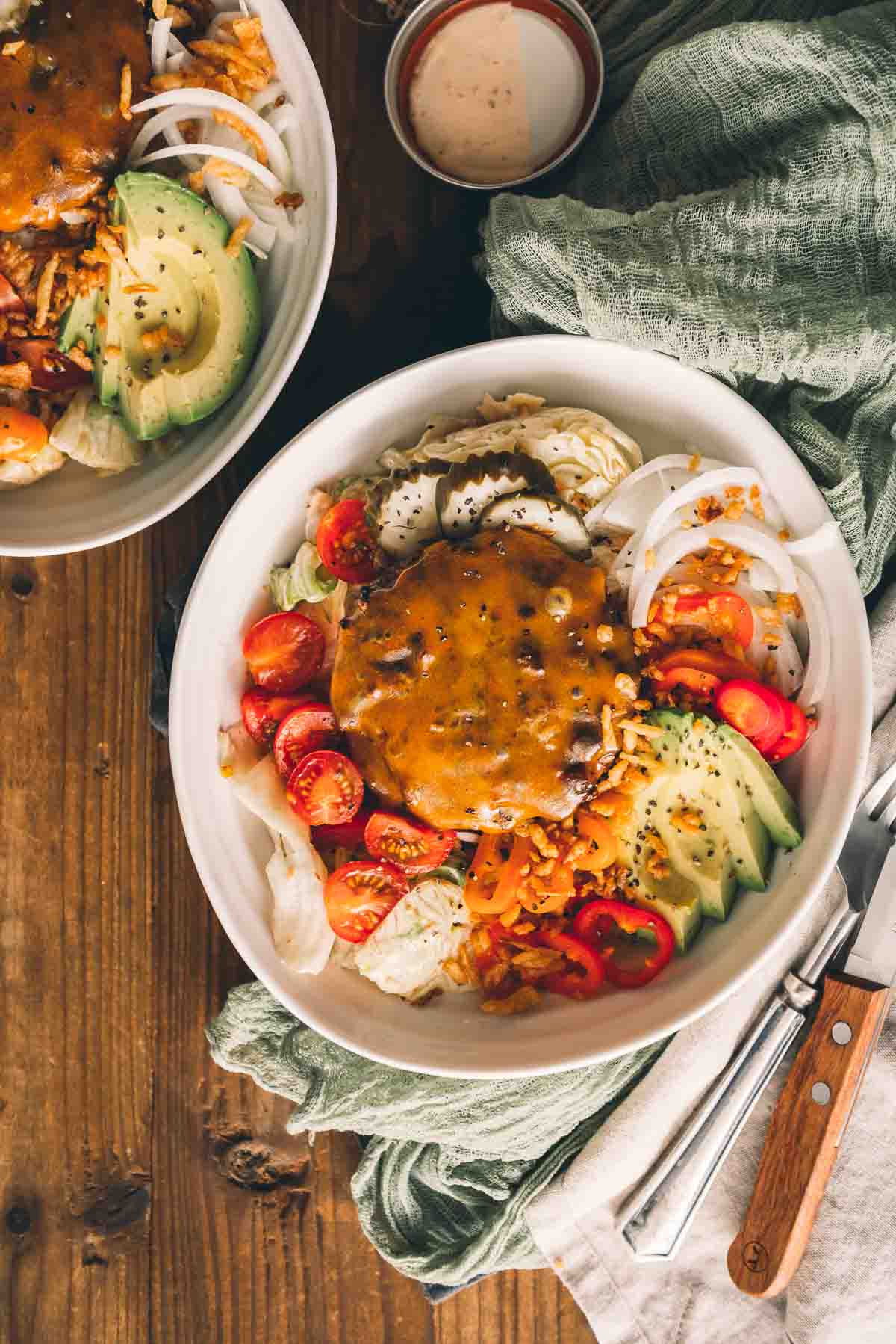 Two bowls of cheeseburger salad on a wooden table.
