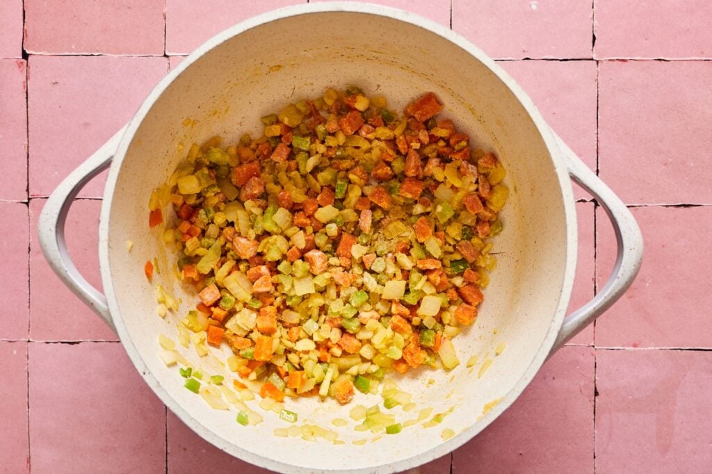 Adding garlic to veggies sauteeing in a dutch oven. 