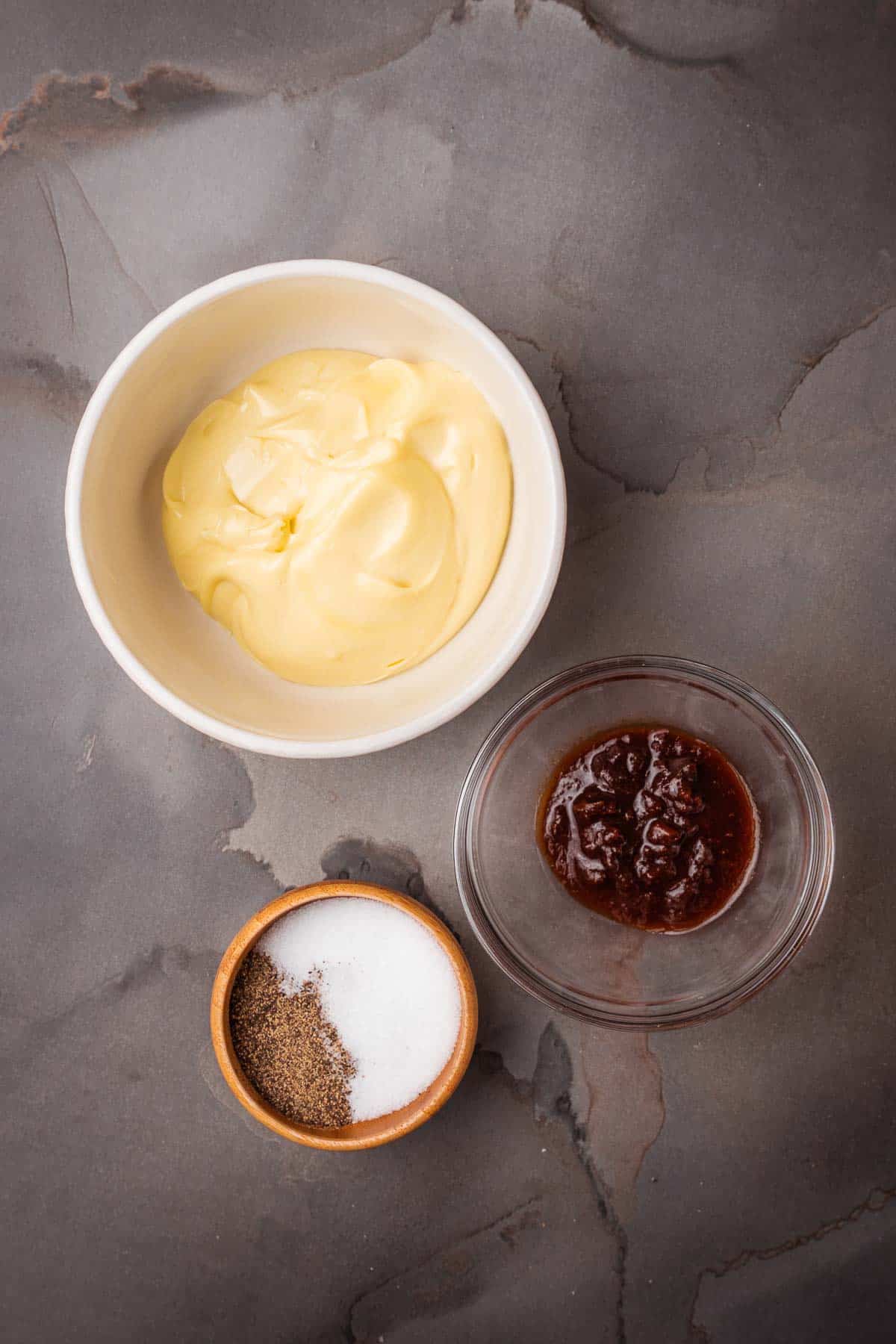 A bowl of aioli, a bowl of chipotle chiles, and a bowl of salt.