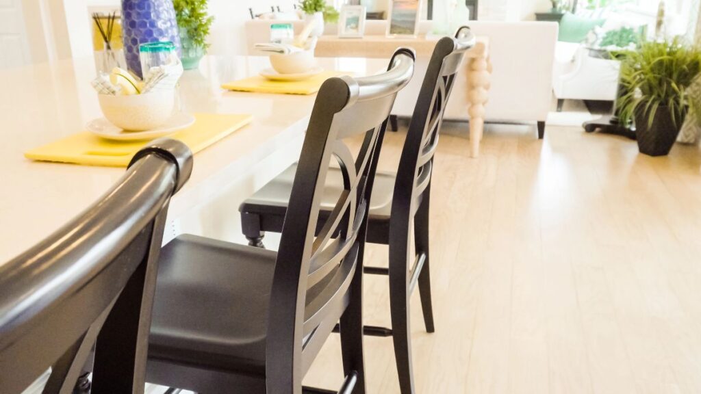 Black dining chairs around a light wooden table in a bright dining room