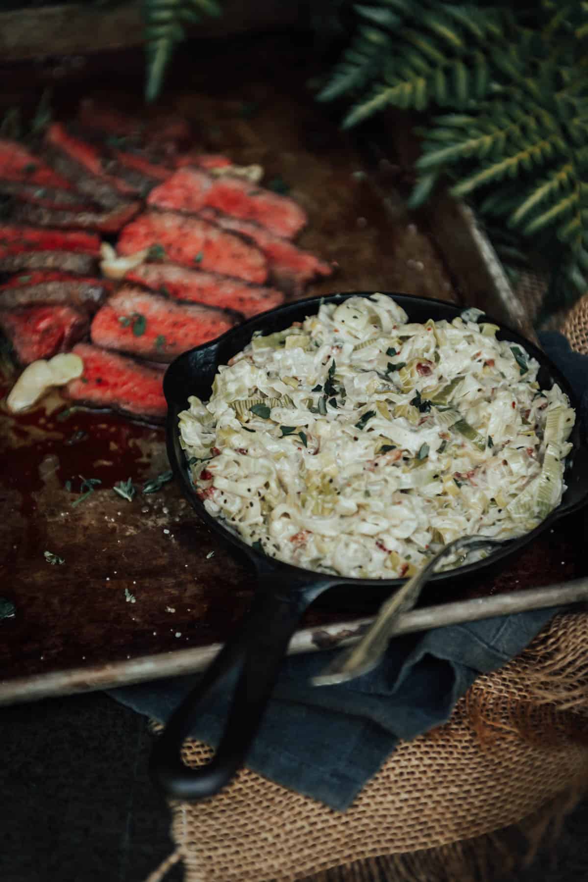 A cast iron skillet with meat and mashed potatoes.
