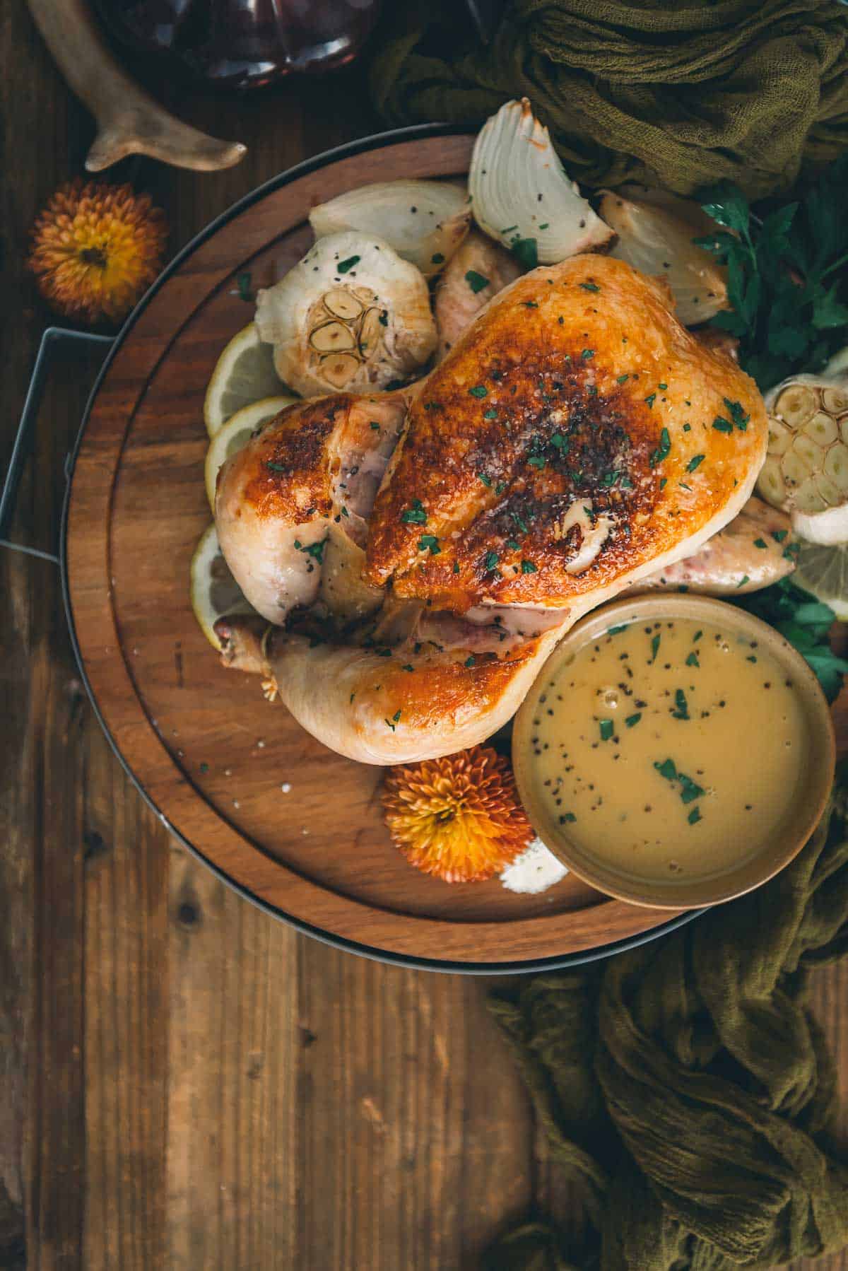 Roasted chicken on a wooden plate with sauce.