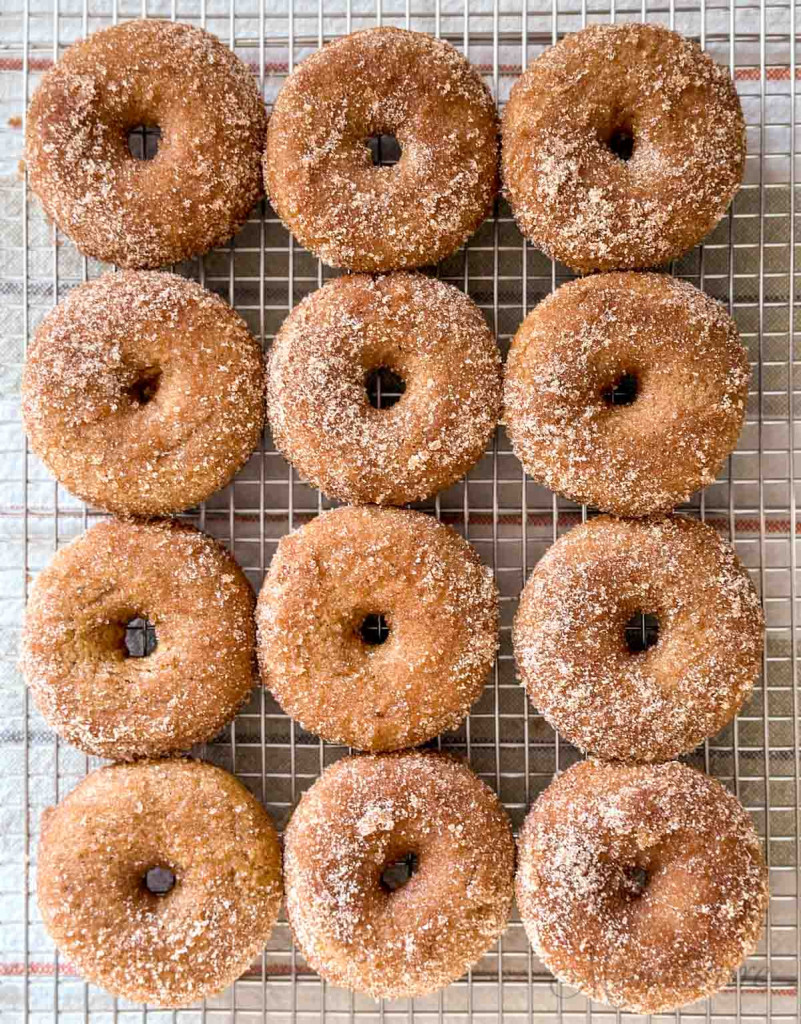 Freshly made apple cider donuts cooling on a wire rack.
