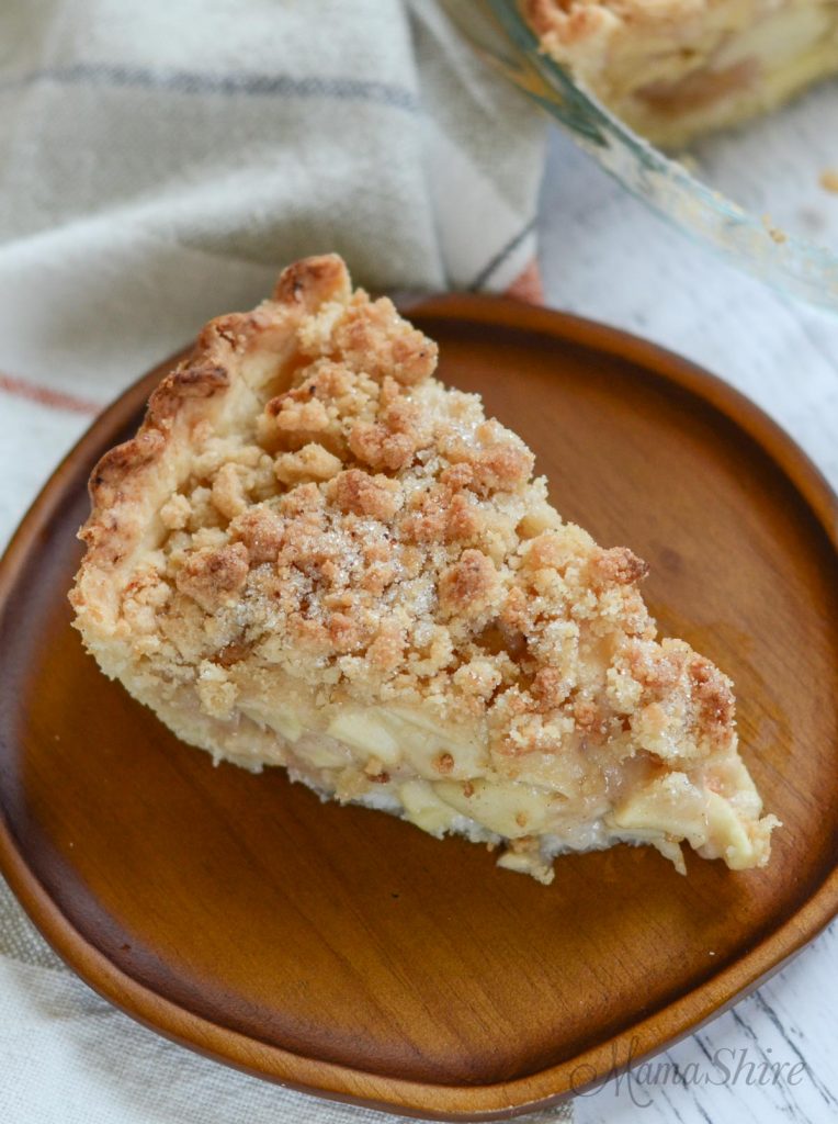 A slice of gluten-free Dutch Apple Pie on a little wooden dessert plate.
