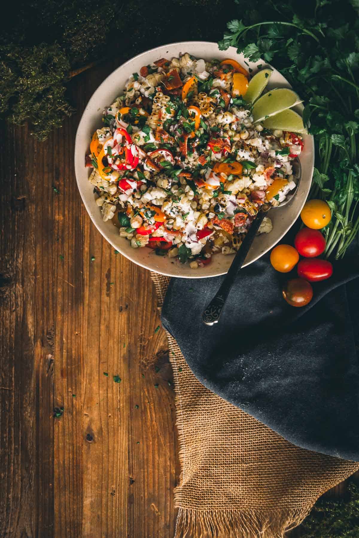 Rustic table with bowl of grilled salad. 