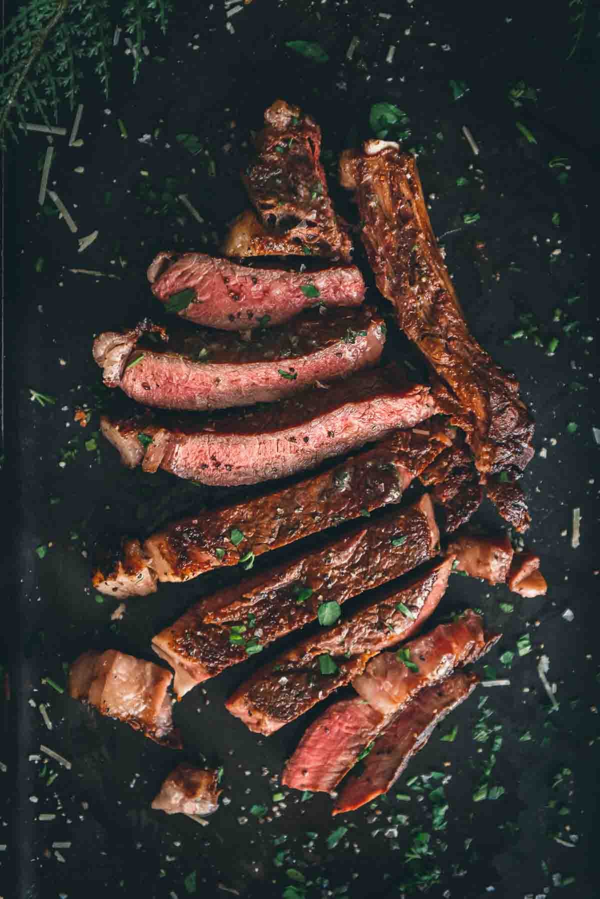 Sliced ribeye steak on a black board.