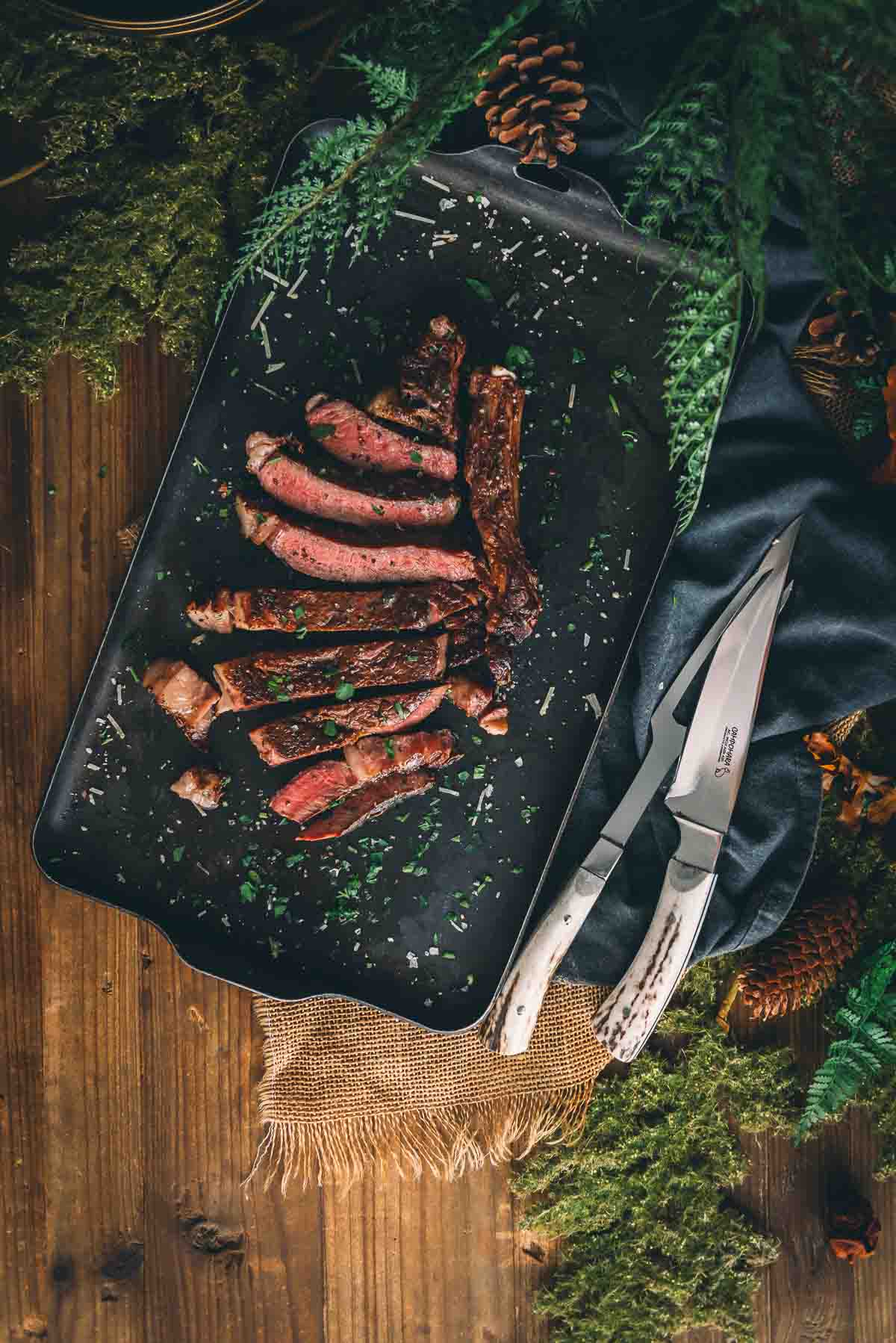 Sliced ribeye steak on a serving tray.