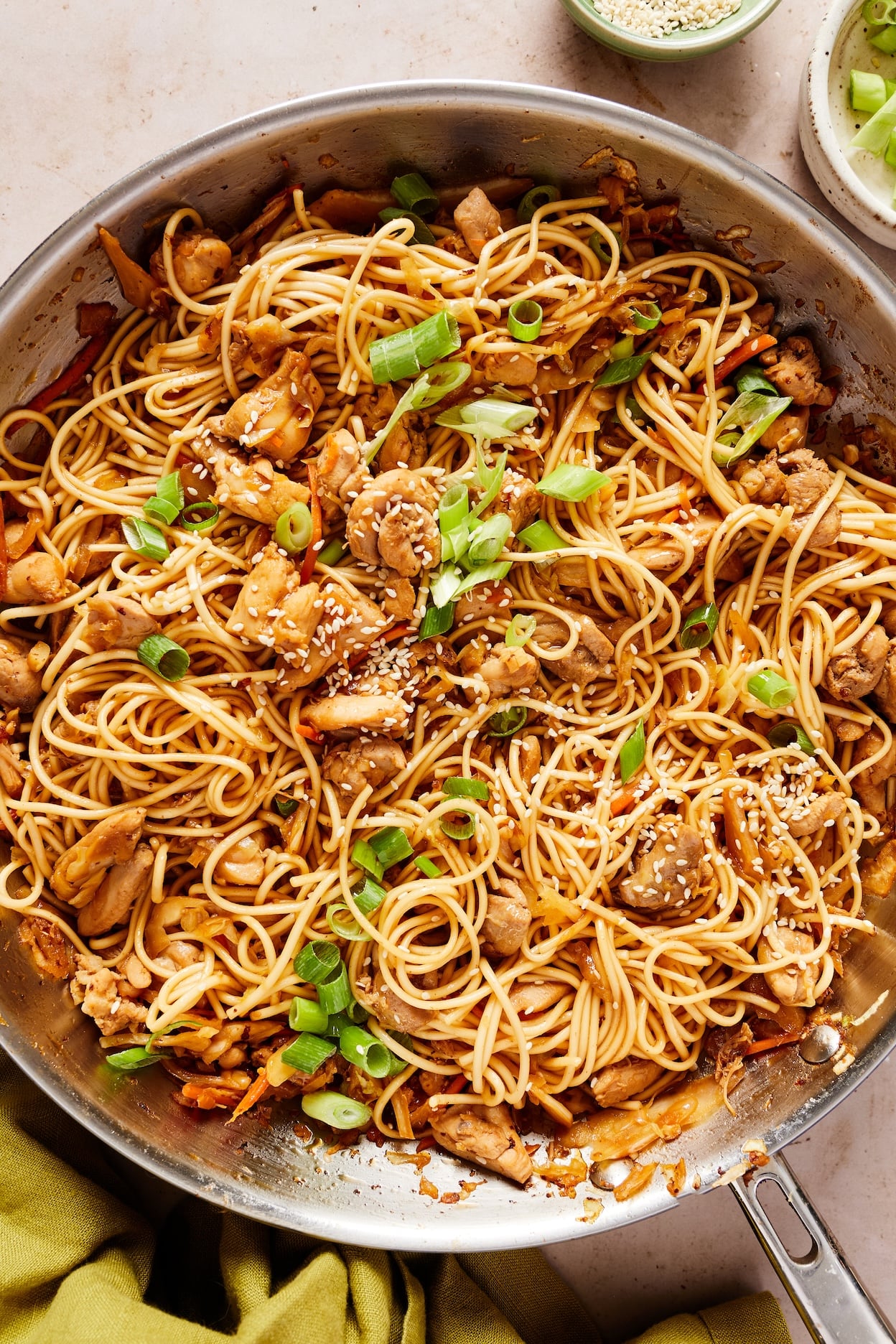 Close-up of honey garlic chicken noodles garnished with green onions and sesame seeds.