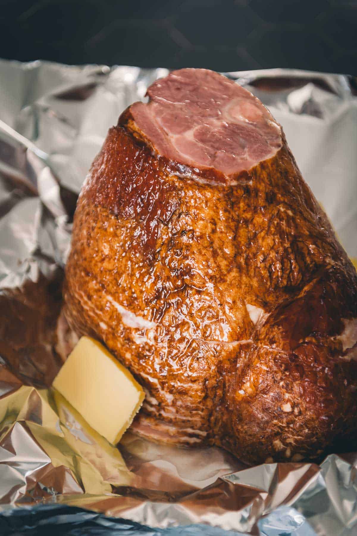 Spiral ham on foil with butter on top.