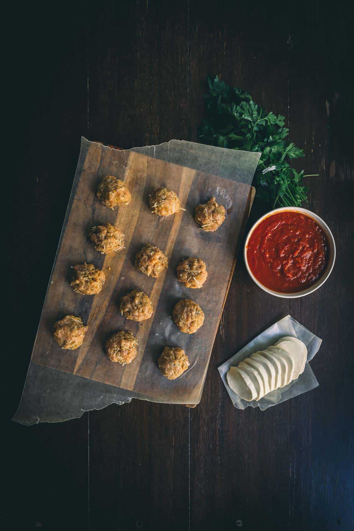 Meatballs rolled and laying on wax paper. 