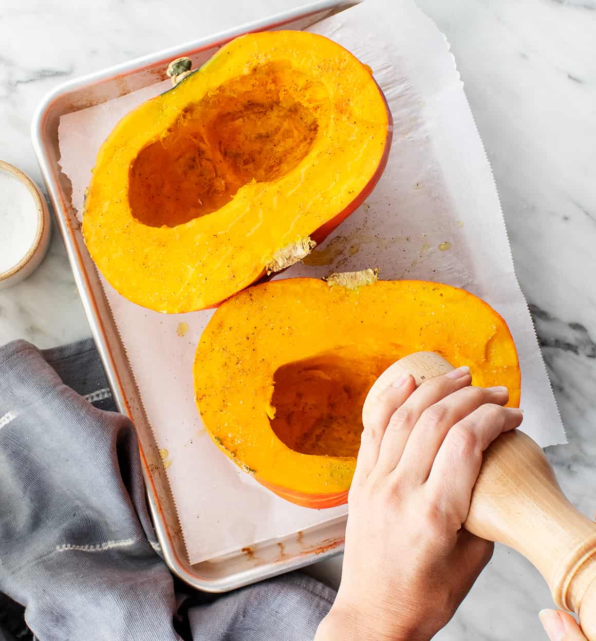 Halved kabocha squash cut-side-up on a baking sheet
