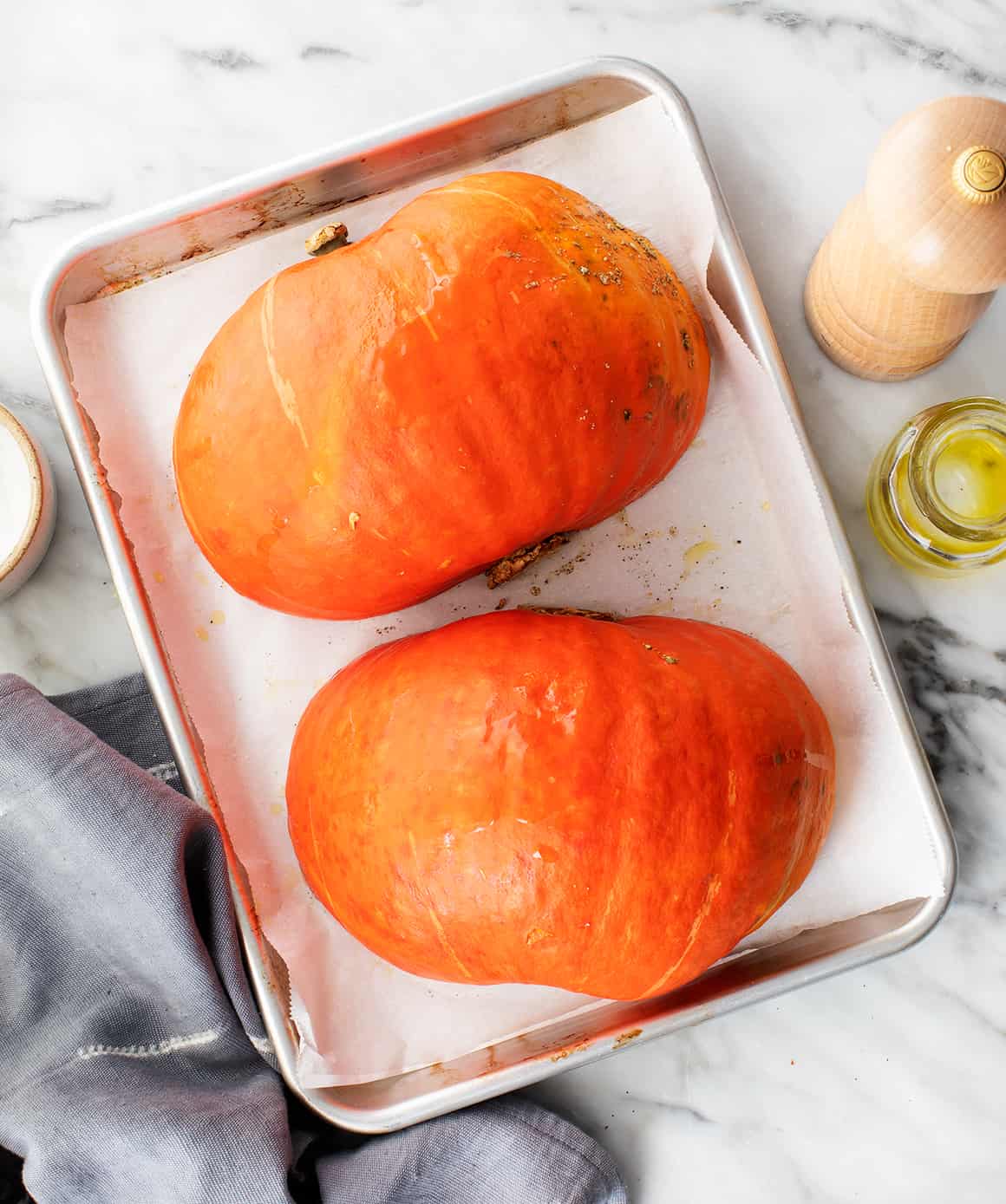 Halved kabocha squash cut-side-down on a baking sheet