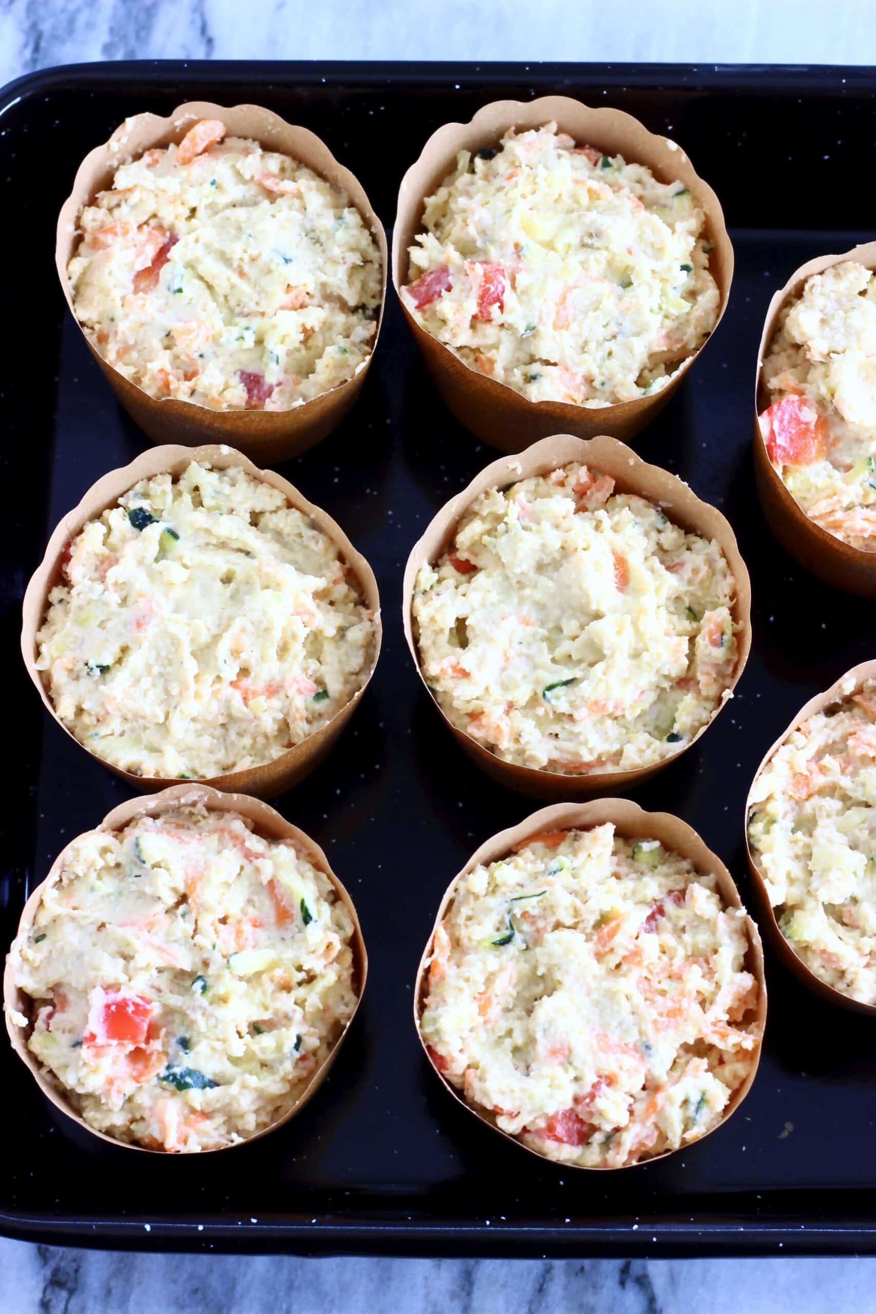 Raw gluten-free vegan savoury vegetable muffins batter in muffin cases in a muffin tin