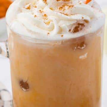 Closeup of a homemade iced pumpkin spice latte with an orange and white striped straw