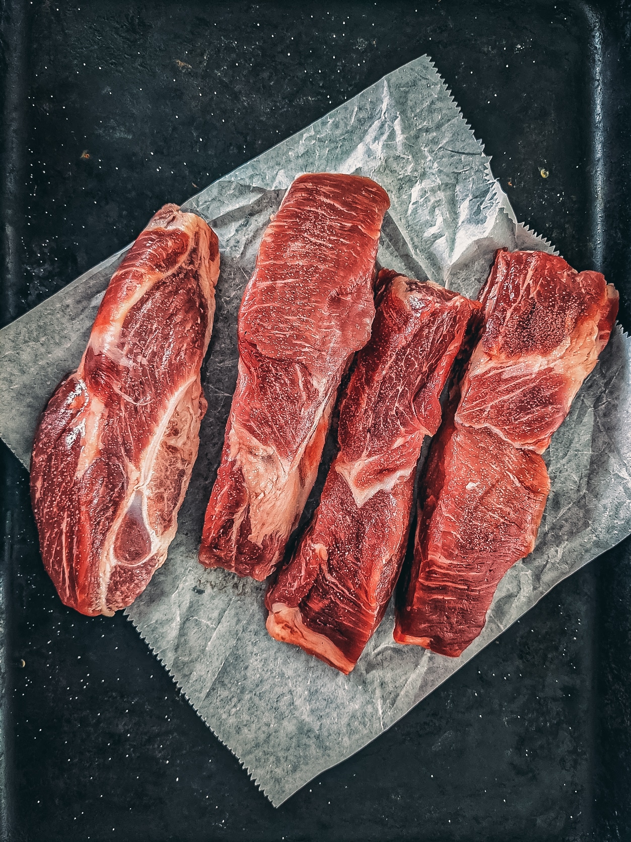 Country style ribs on a black board.
