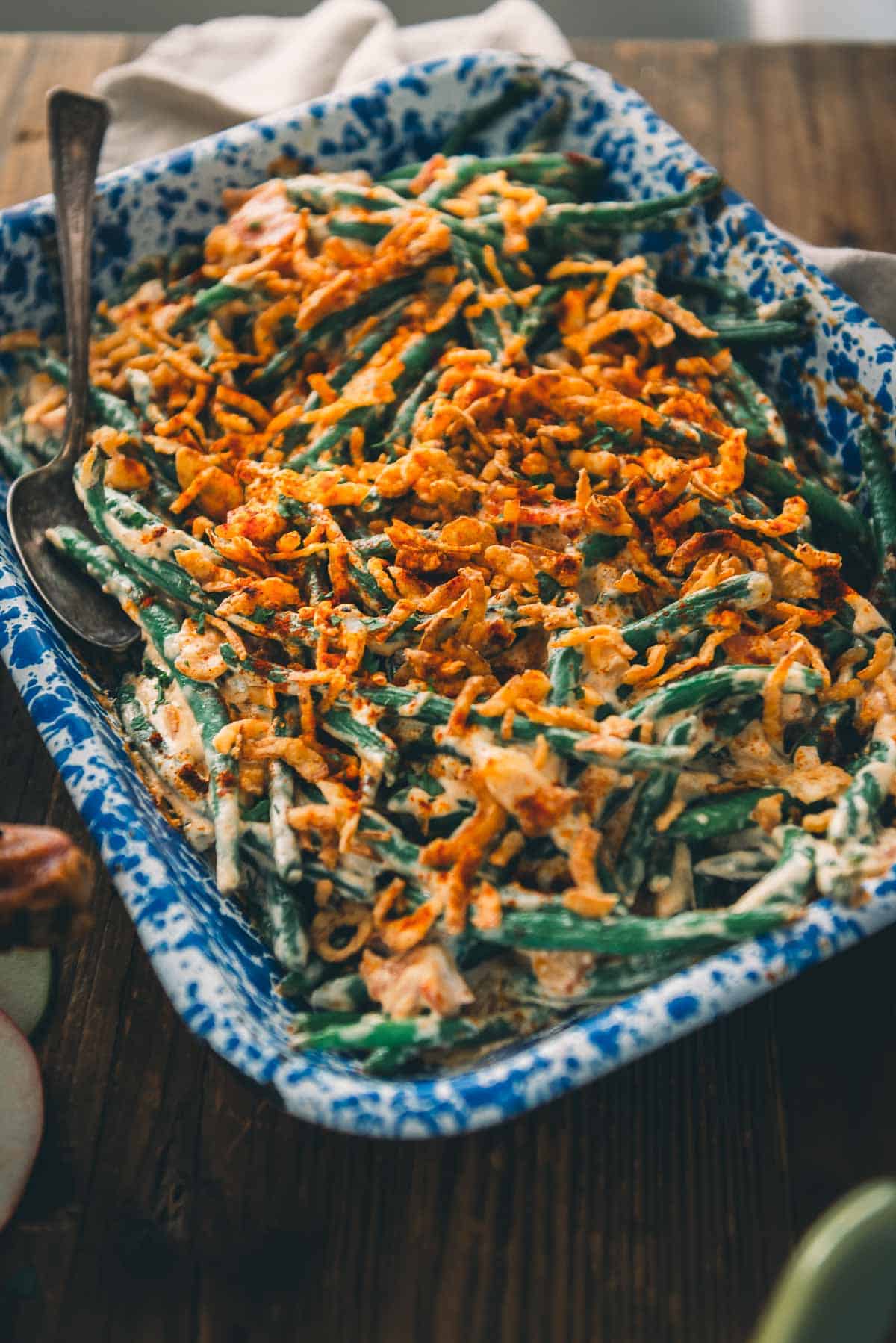 A blue and white dish with green beans and cheese.