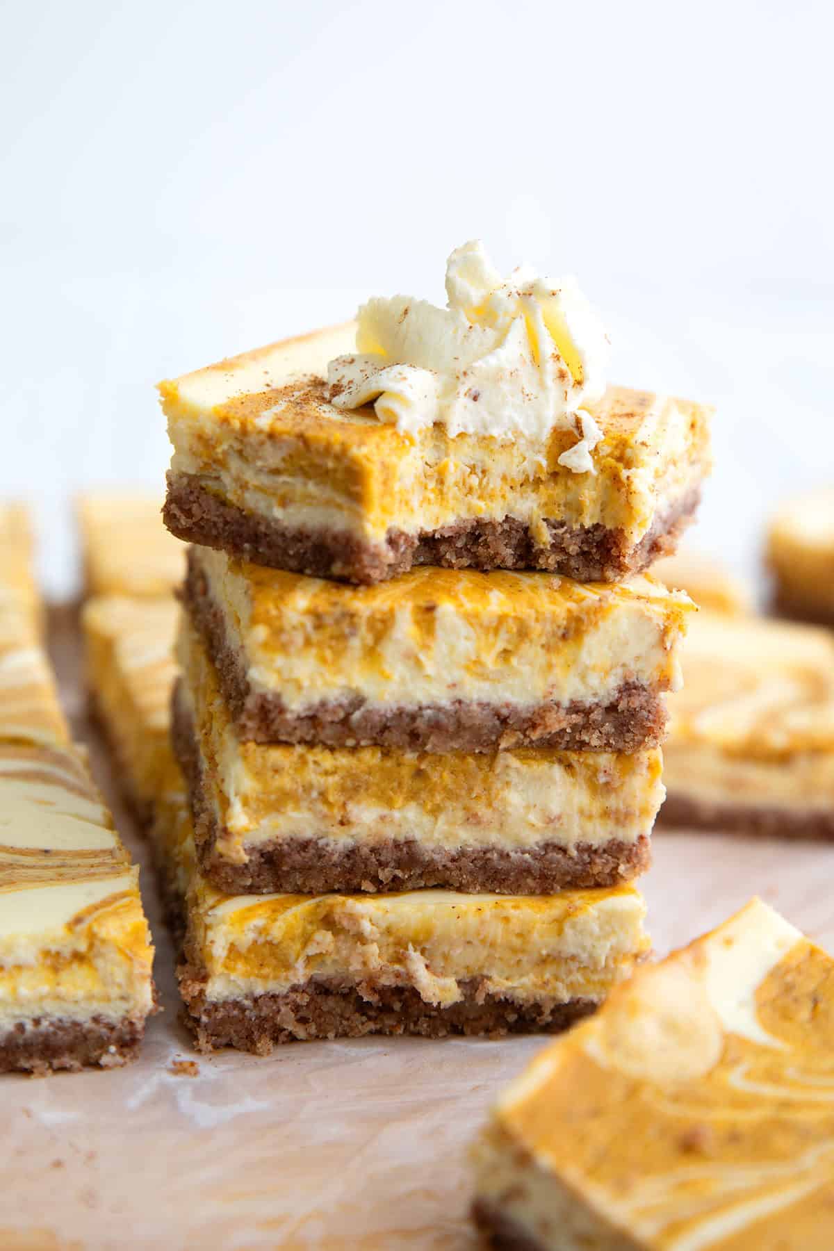 a stack of keto pumpkin cheesecake bars with a bite taken out of the top one.